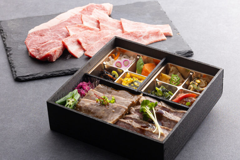 彩り豊かなおかずとお肉を盛り付けたROKUMEIKANのお弁当